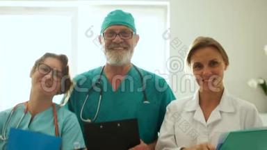 一家家庭诊所的医务人员，<strong>三个</strong>穿着医疗服的<strong>医生</strong>正微笑着看着摄像机